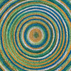 Top-down close-up view of a colorful jute area rug with concentric circles in green, blue, yellow, and natural tones, reversible & eco-friendly.