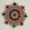 Decorative wall hanging with concentric circles in beige, red, and blue on a white wall.