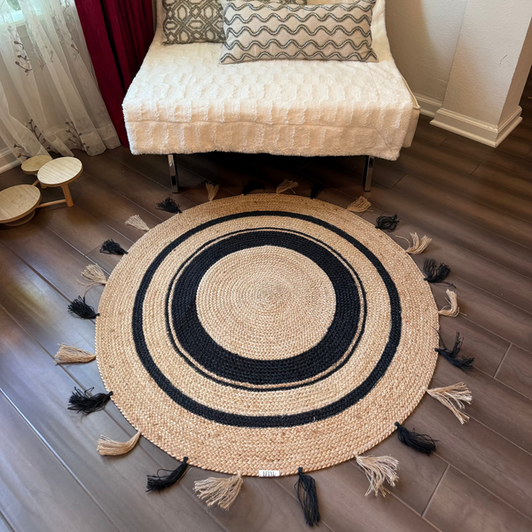 Boho round handwoven jute rug featuring black and natural concentric circles and alternating black and natural tassels.