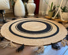 Round handwoven natural jute rug with black concentric circles and black & natural tassels. Boho floor mat.