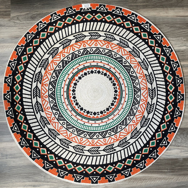 Reversible round natural jute rug with a boho tribal pattern in black, orange, green, and cream. Hand-braided, eco-friendly area rug.